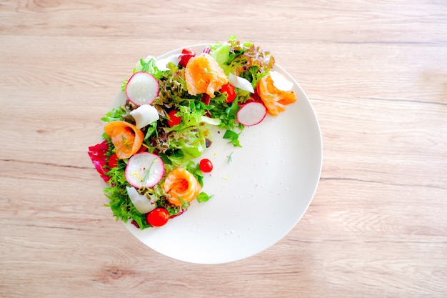 Fresh smoked salmon salad in white plate on wood