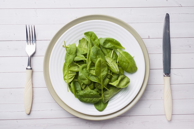 Fresh spinach leaves in a plate on a light table.