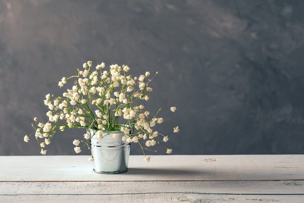 Fresh spring flowers arrangement in metallic bucket on wooden table