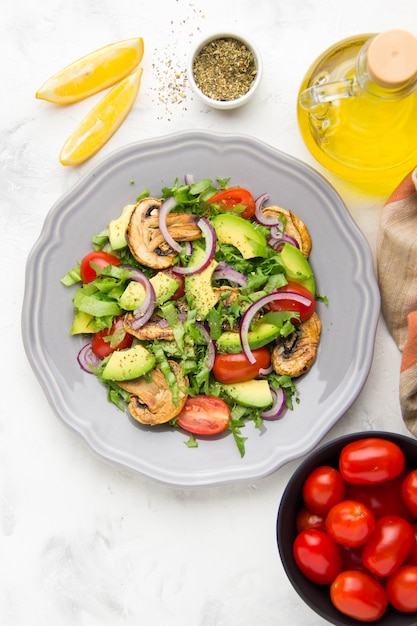 Fresh spring salad with mushrooms, cherry tomatoes, avocado and onions