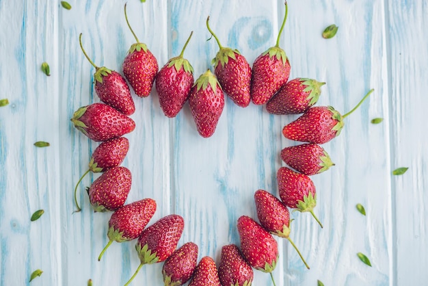 Fresh strawberries array heart shape on old wooden background.