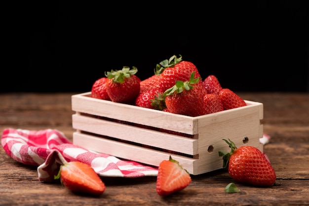 Fresh strawberries in a basket on old wooden table close up