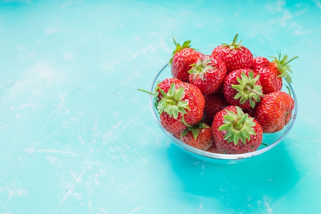 Fresh strawberries in bowl isolated on soft blue.