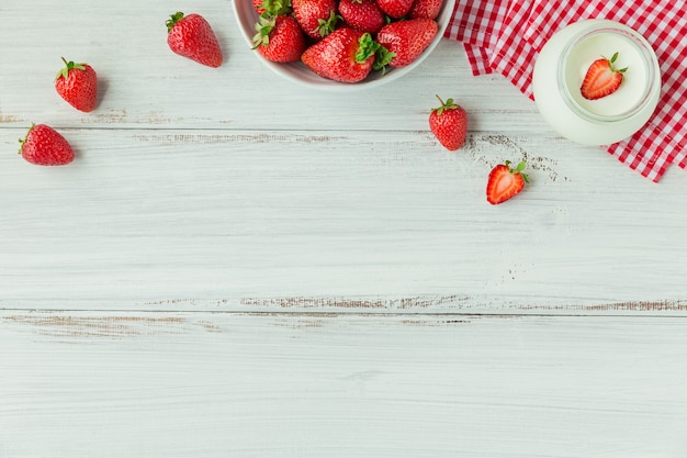 Fresh strawberries on ceramic bowl top view. Healthy food on white wooden table border mockup