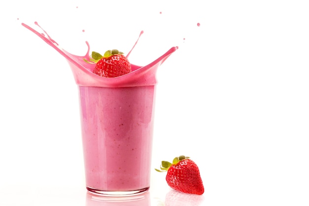 Fresh strawberries falling into a glass to make a healthy strawberry milkshake with copy space