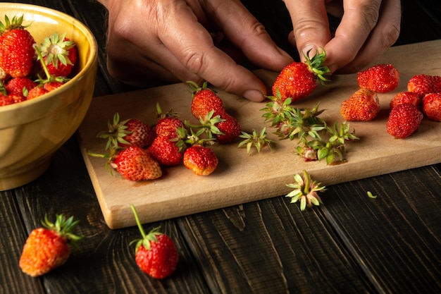 Fresh strawberries in the hands of the chef while preparing a sweet drink in the kitchen