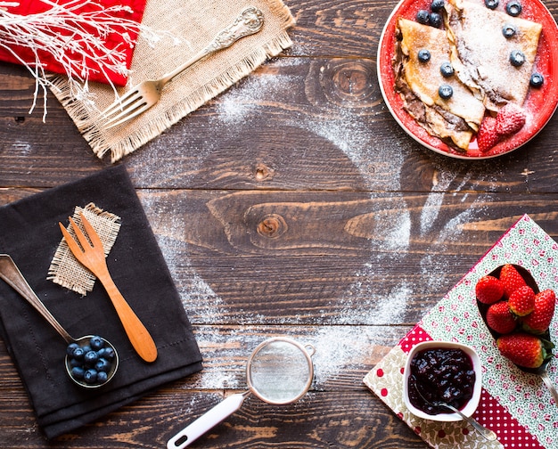 Fresh Strawberries Pancakes or Crepes with berries and chocolate on wooden background