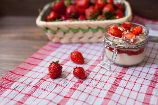 Fresh strawberries with cream and oat flakes in the glass bowl for preparing tasty lunch