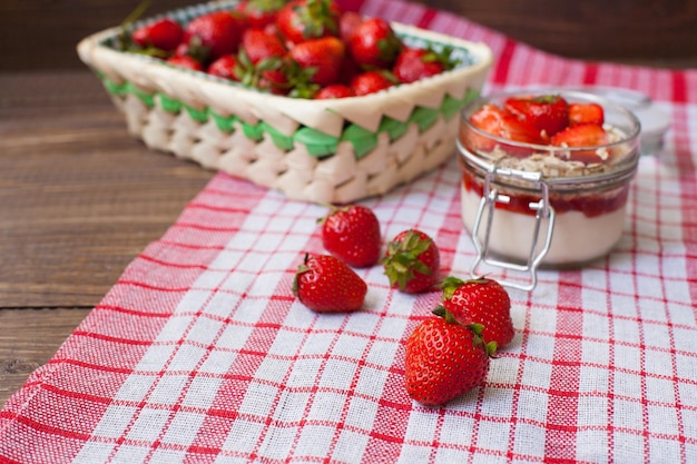 Fresh strawberries with cream and oat flakes in the glass bowl for preparing tasty lunch