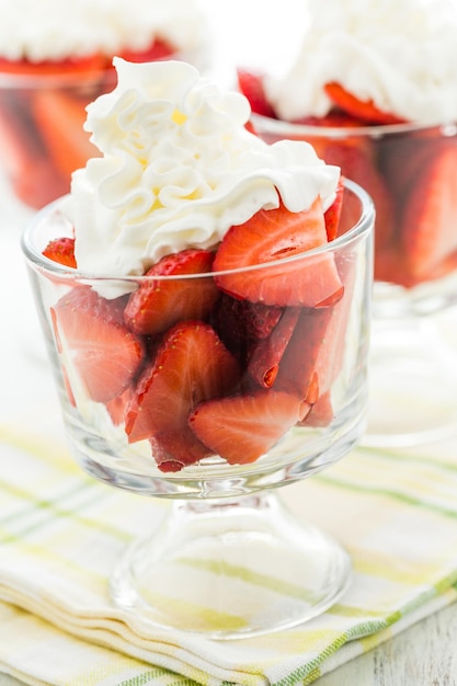 Fresh strawberries with whippes in glass bowls cream for dessert.