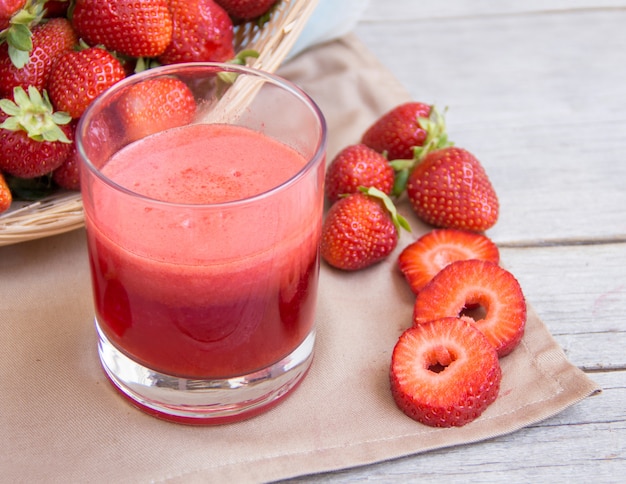 Fresh strawberry smoothie juice and strawberries on a wooden table close up