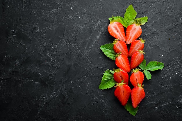 Fresh strawberry with leaves on a black stone background Berries Top view Free space for your text