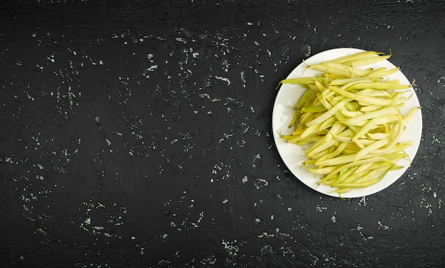 Fresh string beans in a seasoned plate on a dark table. View from above. Copy space