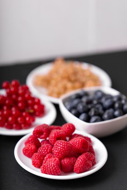 Fresh summer berries in vintage mug over black background, top view