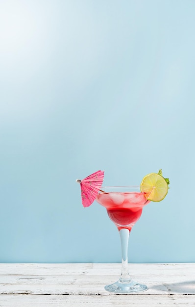 Fresh summer cocktail with strawberry lime and ice cubes on blue background with copy space