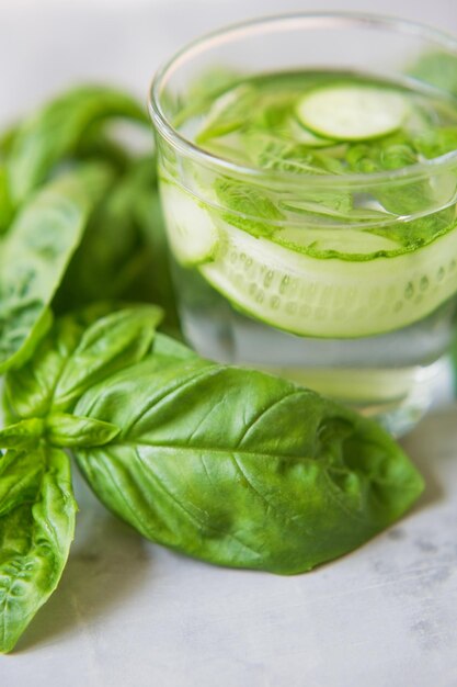 Fresh summer green vegetable cocktail Mocktail with basil leaves anf cucumber Green fresh drink on a grey background