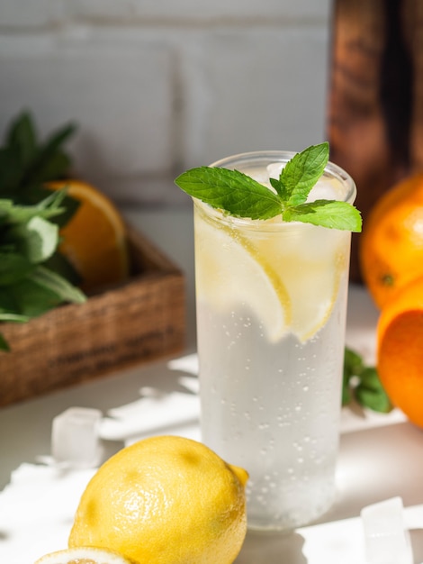 Fresh Summer Homemade citrus lemonade with ice in glass on a white table.