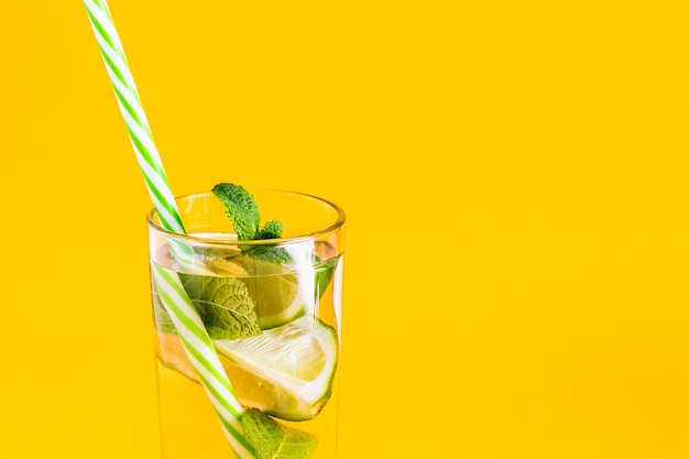 Fresh summer lemonade with water, lime and mint with a straw 