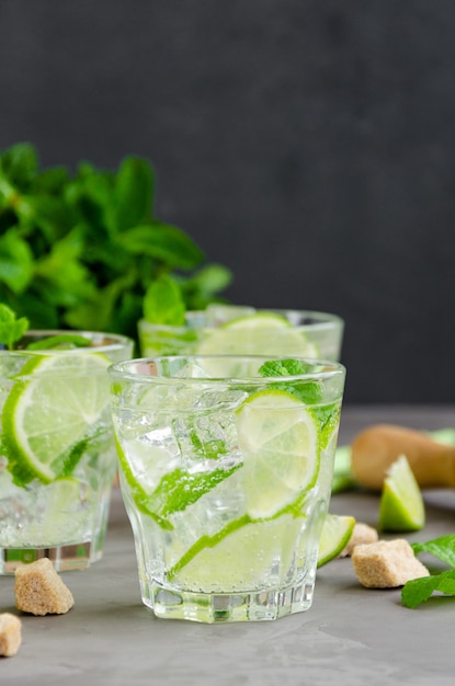 Fresh summer mojito drink with lime slices, mint, ice cubes and brown sugar in a glass