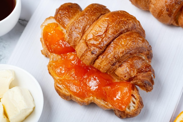 Fresh sweet croissants with butter and apricot jam for breakfast Continental breakfast on a white