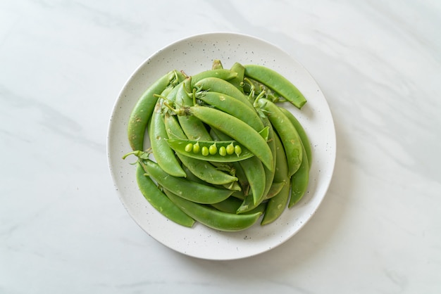 fresh sweet green peas on white plate