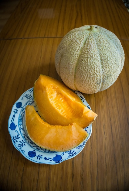 Fresh sweet orange melon on the wooden table selective focus and toned image