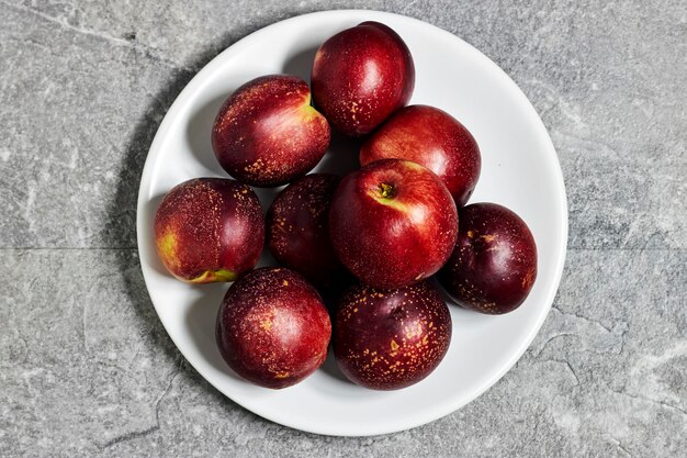 Fresh sweet ripe peaches in white plate on gray grunge background