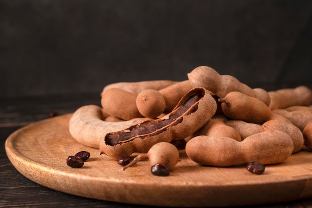 Fresh Tamarind fruits (Tamarindus indica, Indian date) Sweet ripe tamarinds on dark wood background.