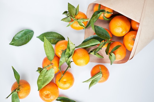 Fresh tangerines with green leaves in a paper bag