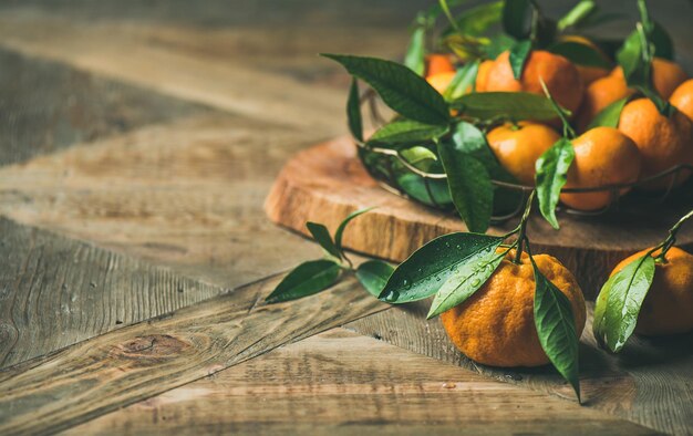 Fresh tangerines with leaves on board copy space