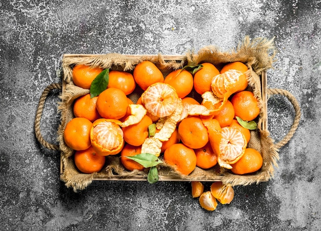 Fresh tangerines on a wooden tray on a rustic background