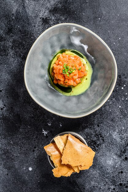 Fresh tartar with salmon, avocado. Black background. Top view.