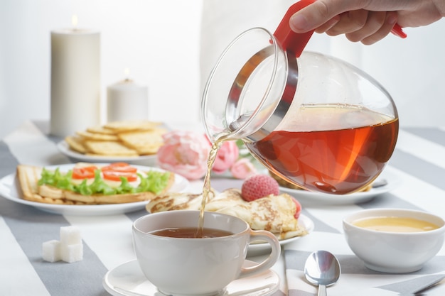 Fresh, tasty breakfast with a sandwich and tea on a light background.