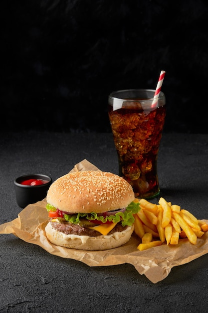 Fresh tasty burger french fries and soft drink on dark background