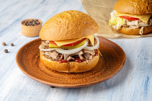 Fresh and tasty burger with roast beef, onion and cheese on blue wooden background. American traditional fastfood. Cheeseburger, Chickenburger