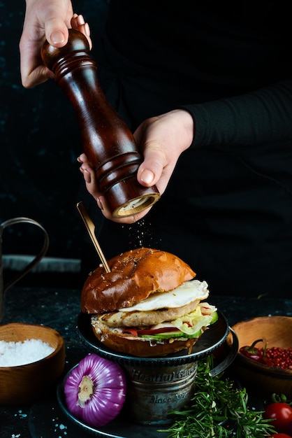 Fresh tasty chicken burger on wood table In the hands On a black background