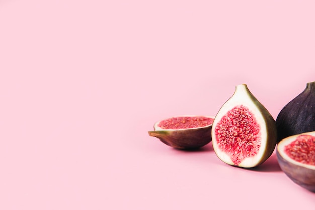 Fresh tasty fig fruit halves with shadow laying down on pink background