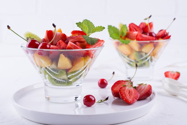 Fresh tasty mix fruit salad in the glass bowl on white table background. Healthy vitamin  breakfast