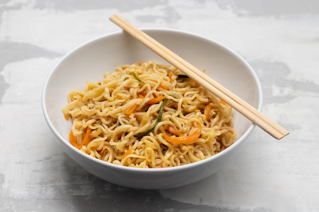 Fresh tasty noodles with vegetables in white bowl