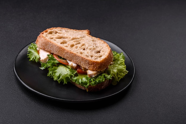 Fresh tasty sandwich with chicken tomatoes and lettuce on a black plate