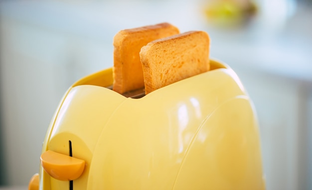 fresh tasty slices of toasts from the yellow toaster on the beautiful kitchen table at home