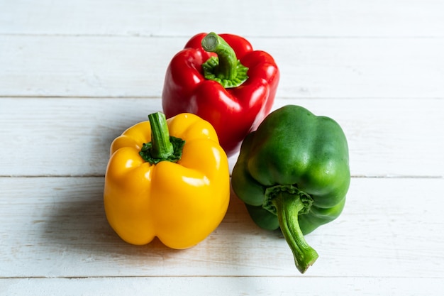 Fresh three color sweet peppers on white  wooden