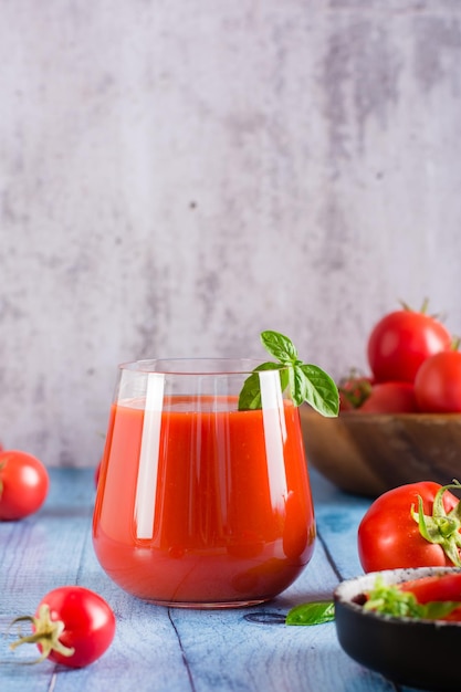 Fresh tomato juice with basil leaves in a glass on the table Homemade organic drinks Vertical view