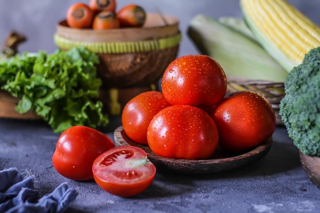 fresh tomatoes in a bowl, around vegetables, carrot, black pepper, corn, broccoli. Slice tomatoes. Harvesting tomatoes. 