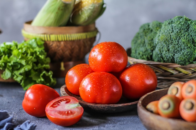 fresh tomatoes in a bowl, around vegetables, carrot, black pepper, corn, broccoli. Slice tomatoes. Harvesting tomatoes. 