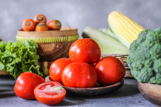 fresh tomatoes in a bowl, around vegetables, carrot, black pepper, corn, broccoli. Slice tomatoes. Harvesting tomatoes. 