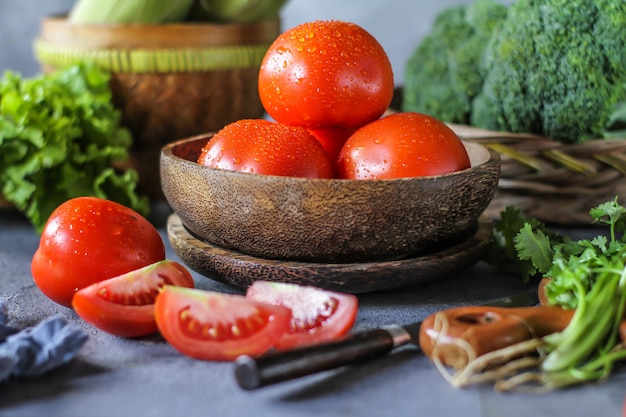 fresh tomatoes in a bowl, around vegetables, carrot, black pepper, corn, broccoli. Slice tomatoes. Harvesting tomatoes. 