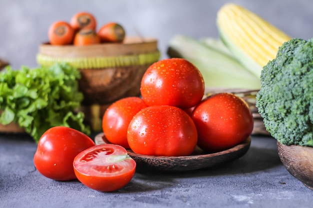 fresh tomatoes in a bowl, around vegetables, carrot, black pepper, corn, broccoli. Slice tomatoes. Harvesting tomatoes. 