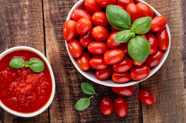 Fresh tomatoes in bowl onold wooden table Tomato background healthy vegetables and basil leaves