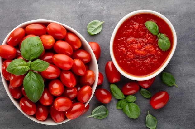 Fresh tomatoes in bowl on pastel table. Tomato background, healthy vegetables and basil leaves.